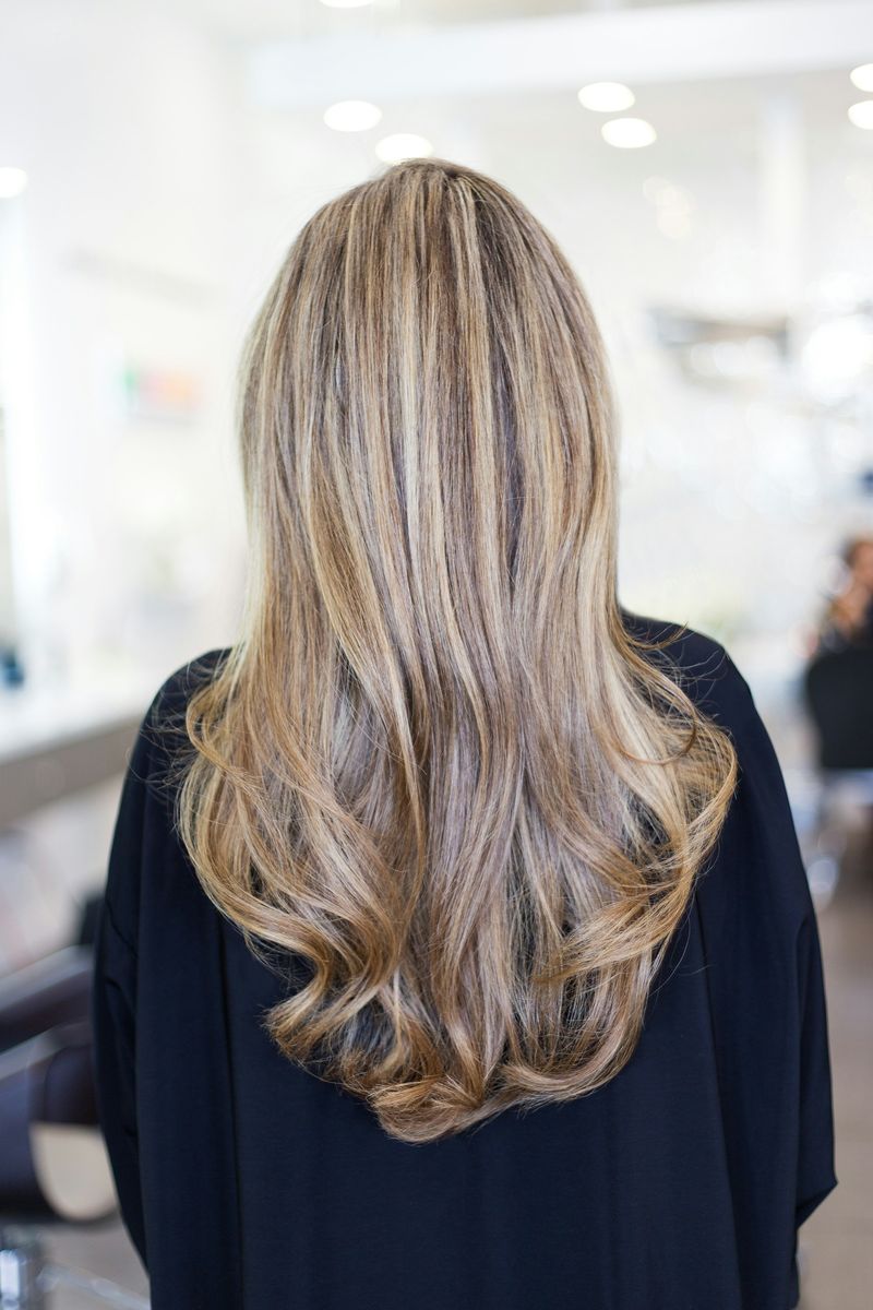 Long wavy hair in a caramel balayage, seen from behind in the salon